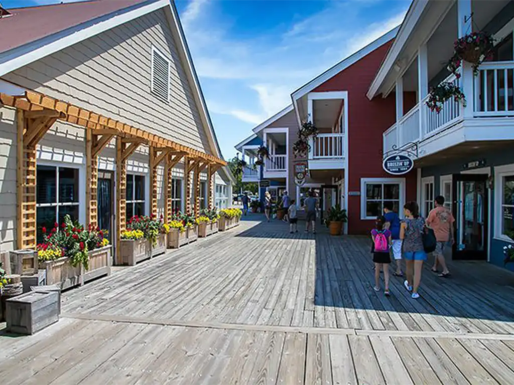 People walking along a wooden boardwalk between shops