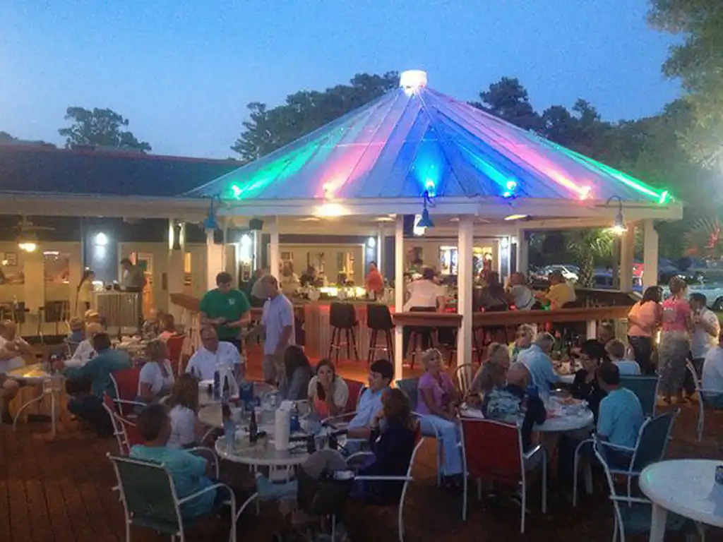 People dine at an outdoor patio bar lit with neon colors