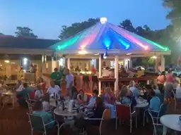 People dine at an outdoor patio bar lit with neon colors