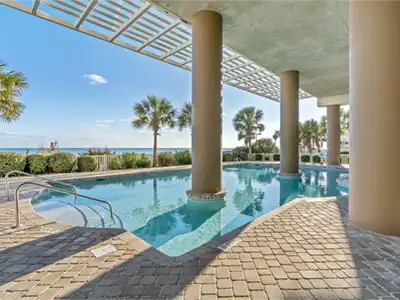Covered resort-style pool with palm trees and peaceful water views