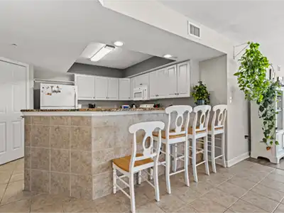 Modern kitchen with white cabinets and a tiled breakfast bar with four stools.