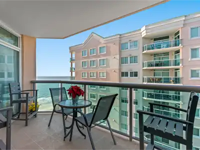 Private balcony with seating, dining table, and partial ocean views