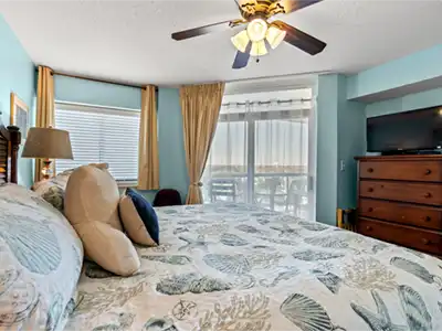 Coastal-inspired bedroom with natural light, TV, and private balcony access